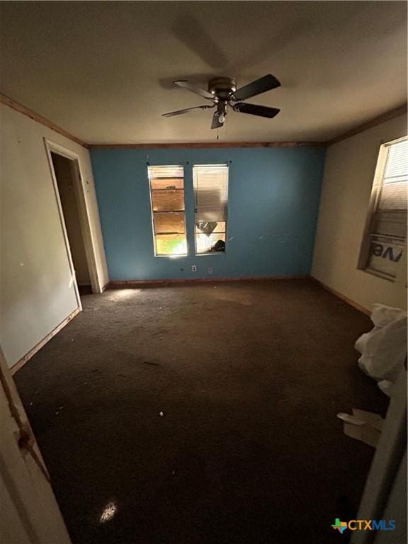 carpeted spare room with crown molding, a ceiling fan, and baseboards