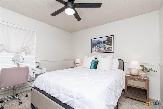 carpeted bedroom with a textured ceiling and a ceiling fan