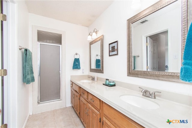 full bath featuring double vanity, a stall shower, visible vents, and a sink