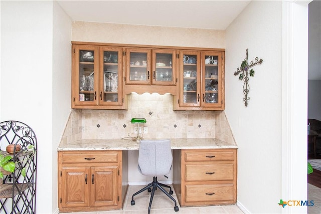 office featuring light tile patterned floors, built in study area, and baseboards