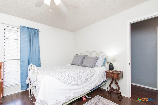 bedroom with a ceiling fan, a textured ceiling, baseboards, and wood finished floors