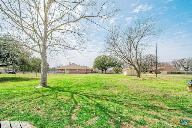 view of yard featuring an outbuilding, a shed, and fence