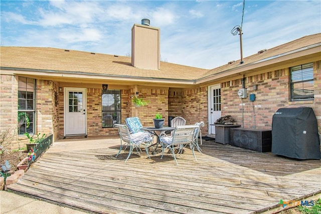 wooden terrace featuring outdoor dining space and area for grilling