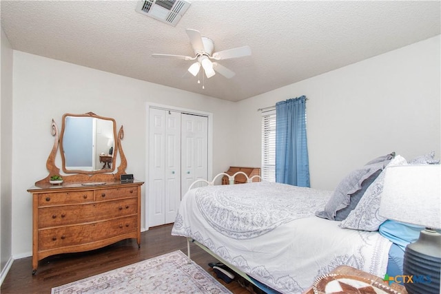 bedroom with a textured ceiling, a closet, wood finished floors, and visible vents