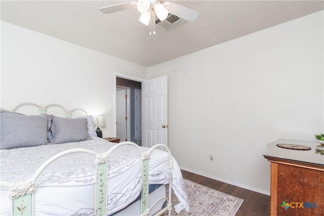 bedroom featuring visible vents, a ceiling fan, a textured ceiling, wood finished floors, and baseboards