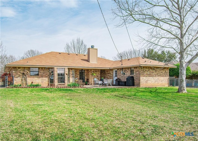 back of house with brick siding, fence, a patio, and a lawn