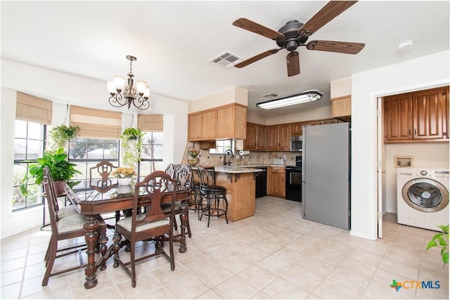 dining space with a healthy amount of sunlight, washer / dryer, visible vents, and ceiling fan with notable chandelier