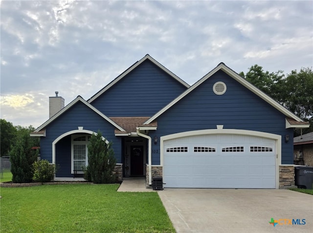 102 Lexington Ln, Victoria, TX 77901 - view of front facade with driveway, a garage, stone siding, a front yard, and a chimney