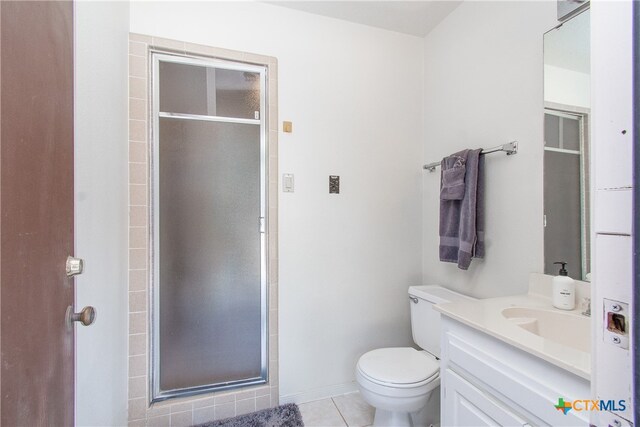 bathroom with toilet, vanity, tile patterned floors, and a shower with door