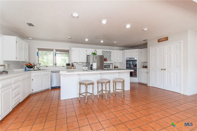 kitchen with stainless steel appliances, white cabinetry, and a kitchen island