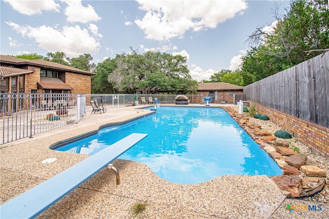 view of swimming pool featuring a patio area and a diving board