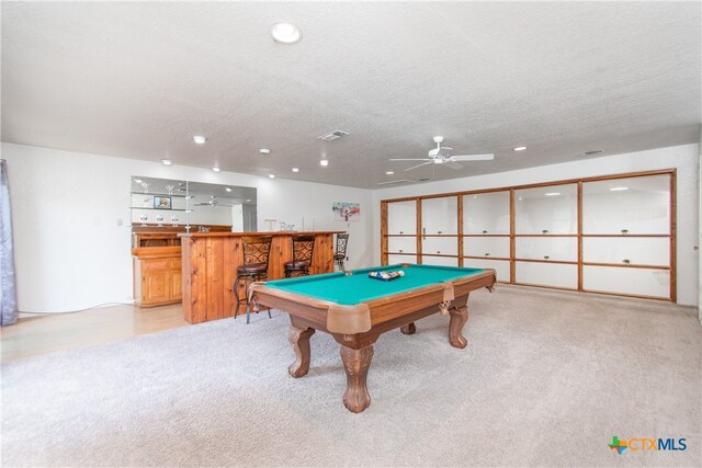 game room featuring bar area, a textured ceiling, light colored carpet, ceiling fan, and billiards