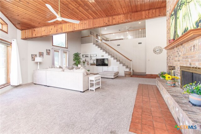 carpeted living room featuring a fireplace, ceiling fan, a high ceiling, and wood ceiling