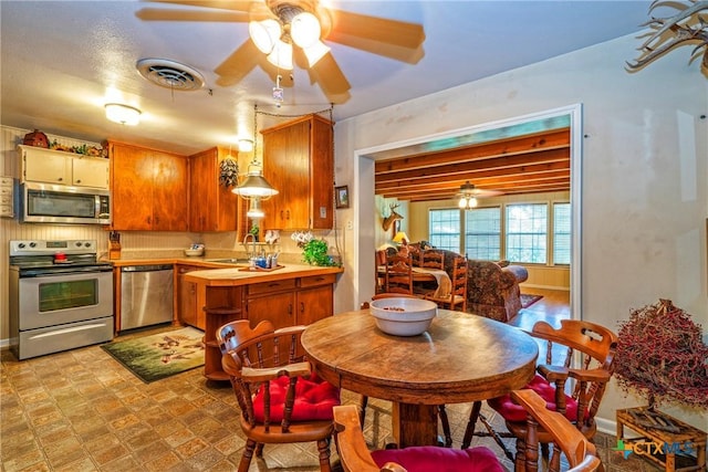 808 E Randall St, Beeville, TX 78102 - kitchen featuring appliances with stainless steel finishes, ceiling fan, light countertops, and brown cabinetry