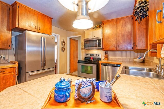 808 E Randall St, Beeville, TX 78102 - kitchen with appliances with stainless steel finishes, tile countertops, and brown cabinets