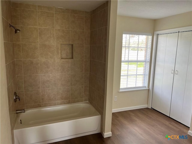 bathroom featuring shower / washtub combination, a wealth of natural light, baseboards, and wood finished floors