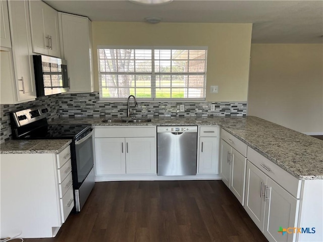 kitchen featuring decorative backsplash, appliances with stainless steel finishes, a sink, light stone countertops, and a peninsula