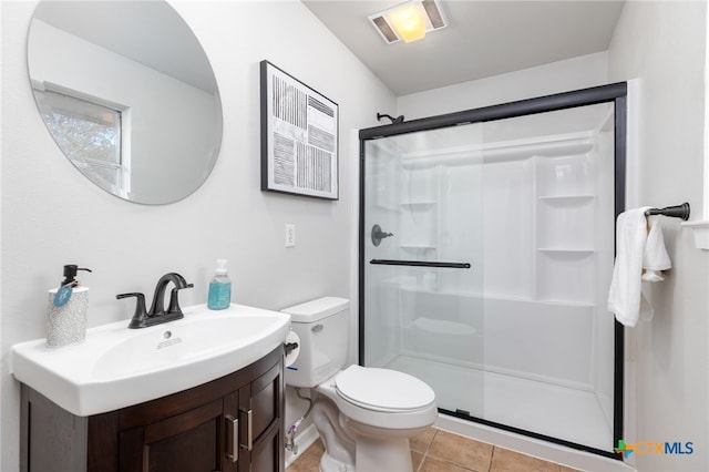 bathroom featuring tile patterned flooring, vanity, toilet, and walk in shower