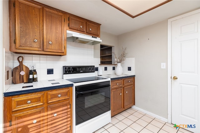 kitchen with decorative backsplash, white range with electric cooktop, tile counters, and light tile patterned flooring