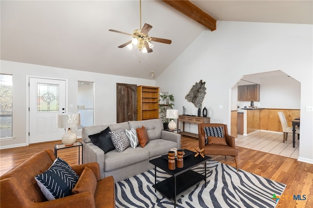 living room featuring beam ceiling, ceiling fan, high vaulted ceiling, and light wood-type flooring