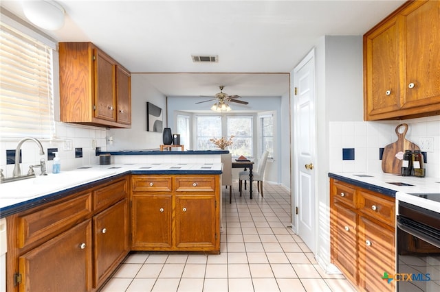 kitchen with decorative backsplash, ceiling fan, kitchen peninsula, and sink