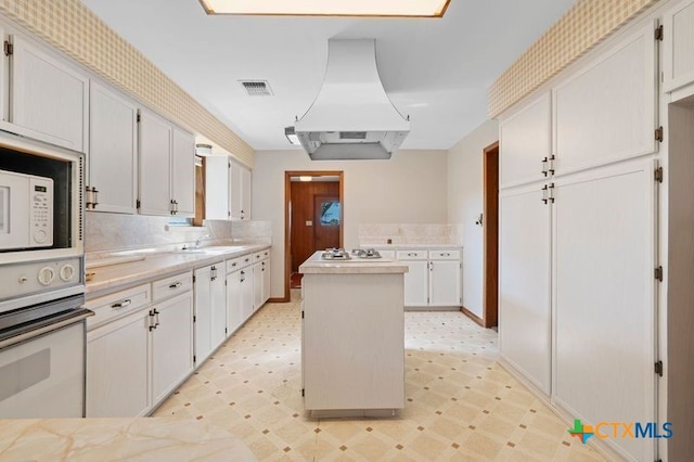 kitchen with white appliances, white cabinetry, ventilation hood, and a kitchen island