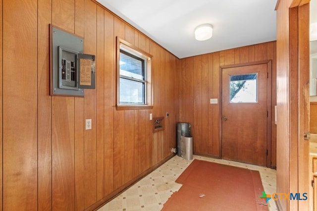 doorway to outside with electric panel and wood walls