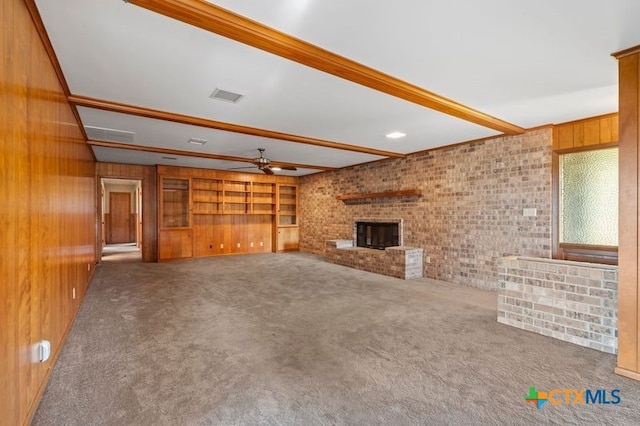 unfurnished living room featuring a brick fireplace, beamed ceiling, carpet floors, and wooden walls