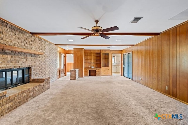 unfurnished living room featuring wood walls, beamed ceiling, and carpet flooring