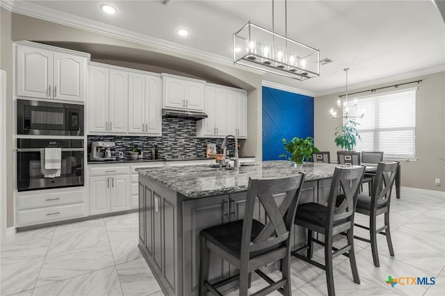 kitchen with dark stone counters, a chandelier, black appliances, ornamental molding, and a kitchen breakfast bar