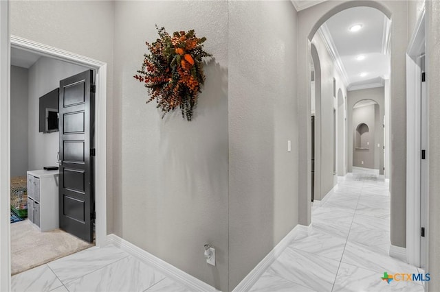 hallway with ornamental molding, arched walkways, marble finish floor, and baseboards