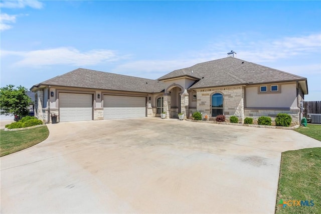 french country inspired facade featuring central air condition unit, a garage, stone siding, concrete driveway, and stucco siding