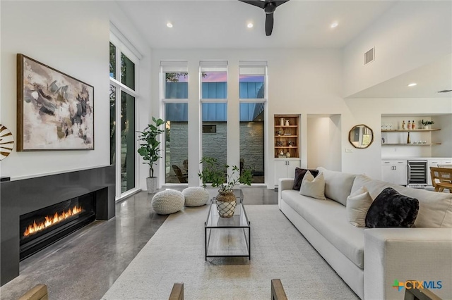 living room featuring built in features, indoor bar, wine cooler, and concrete floors