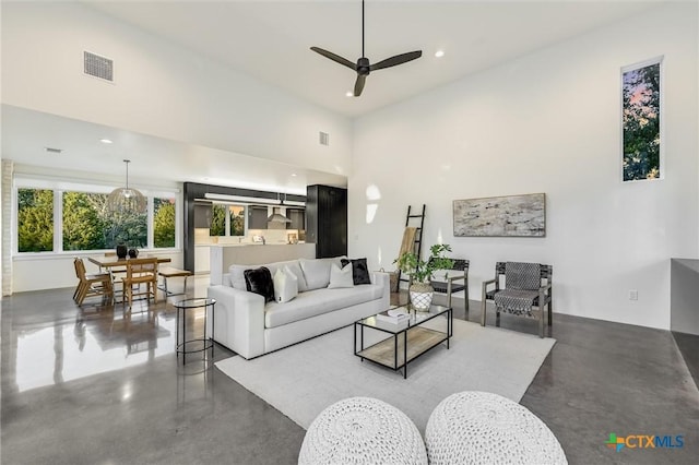 living room with ceiling fan, concrete floors, and a high ceiling