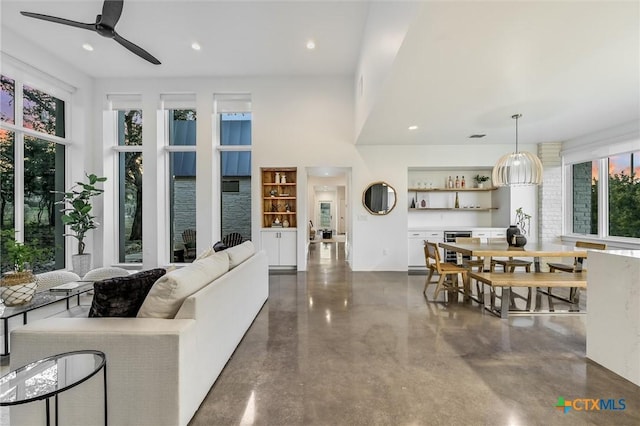 living room featuring ceiling fan and a towering ceiling