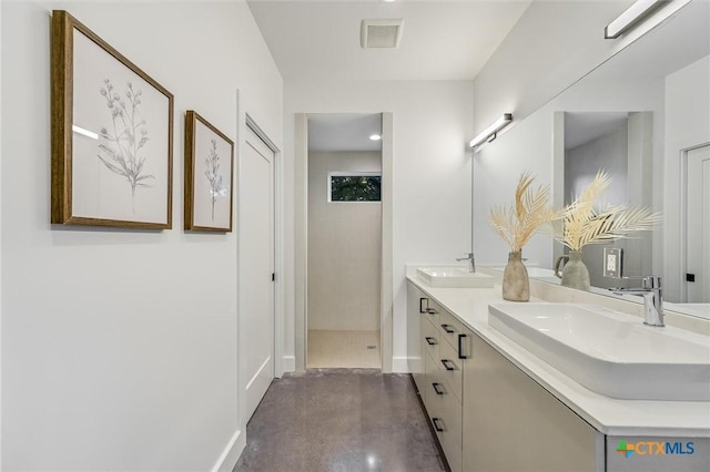 bathroom with tiled shower, concrete floors, and vanity