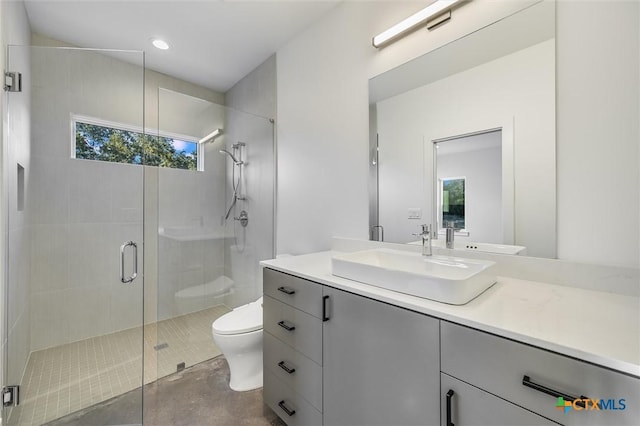 bathroom with toilet, vanity, and a shower with door