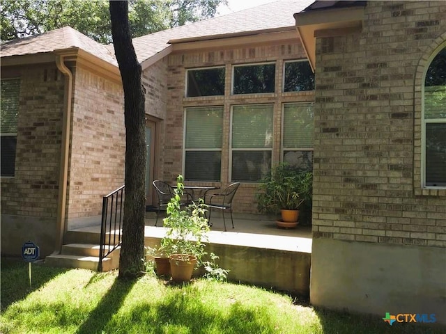 3241 Ranch Park Trl, Round Rock, TX 78681 - view of exterior entry with brick siding, a patio area, and a shingled roof