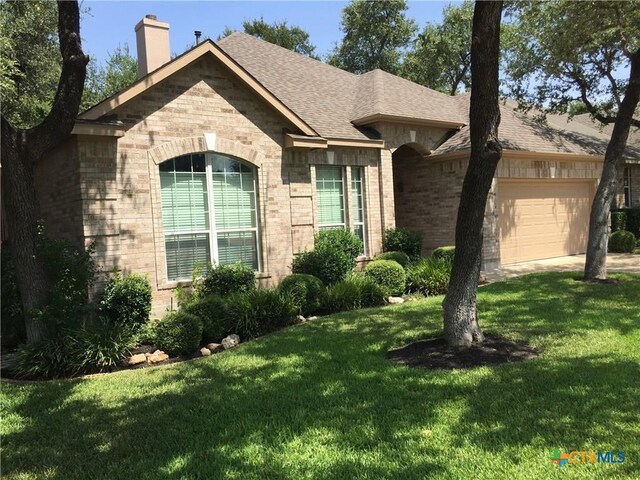 3241 Ranch Park Trl, Round Rock, TX 78681 - view of front of house with an attached garage, brick siding, a chimney, a front yard, and roof with shingles