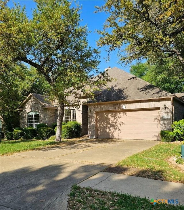 3241 Ranch Park Trl, Round Rock, TX 78681 - view of property hidden behind natural elements featuring a garage, concrete driveway, and stone siding