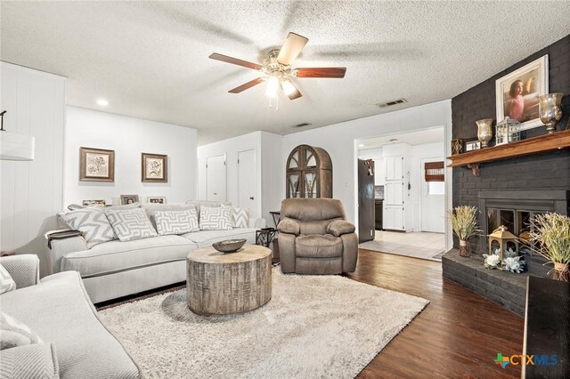 109 E Moonlight Dr, Robinson, TX 76706 - living room featuring a textured ceiling, ceiling fan, dark hardwood / wood-style flooring, and a fireplace