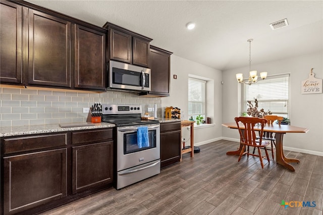 kitchen featuring appliances with stainless steel finishes, dark brown cabinetry, dark hardwood / wood-style floors, decorative backsplash, and a chandelier