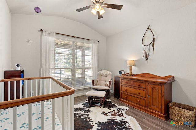 bedroom featuring a crib, wood-type flooring, ceiling fan, and lofted ceiling