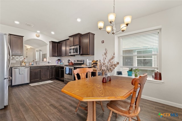 dining space featuring vaulted ceiling, an inviting chandelier, and dark hardwood / wood-style flooring