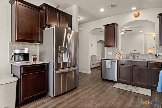 kitchen with backsplash, appliances with stainless steel finishes, vaulted ceiling, dark wood-type flooring, and ceiling fan