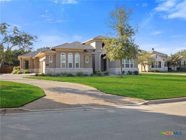 mediterranean / spanish home featuring driveway, a front yard, and stucco siding