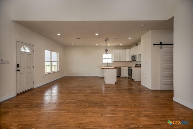 177 Powderhorn Ln, Port Lavaca, TX 77979 - unfurnished living room with a barn door, dark wood-type flooring, and recessed lighting