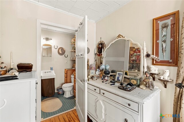 bathroom featuring toilet, vanity, hardwood / wood-style floors, and crown molding