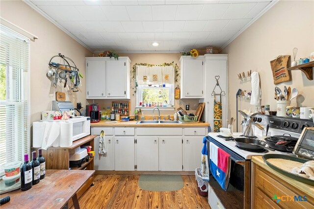 kitchen with light hardwood / wood-style floors, sink, crown molding, white cabinets, and electric range