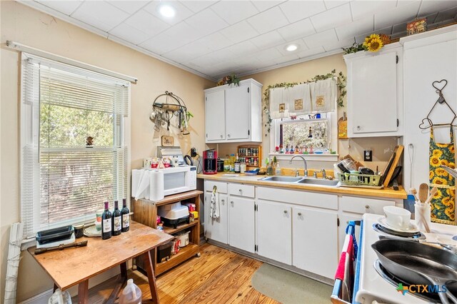 kitchen with white cabinets, light hardwood / wood-style floors, and sink